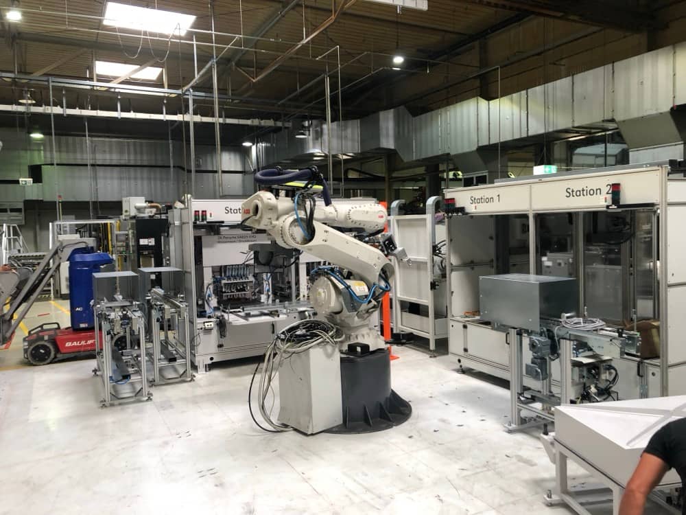 Robotické pracoviště s bílým ramenem ve výrobním závodě.