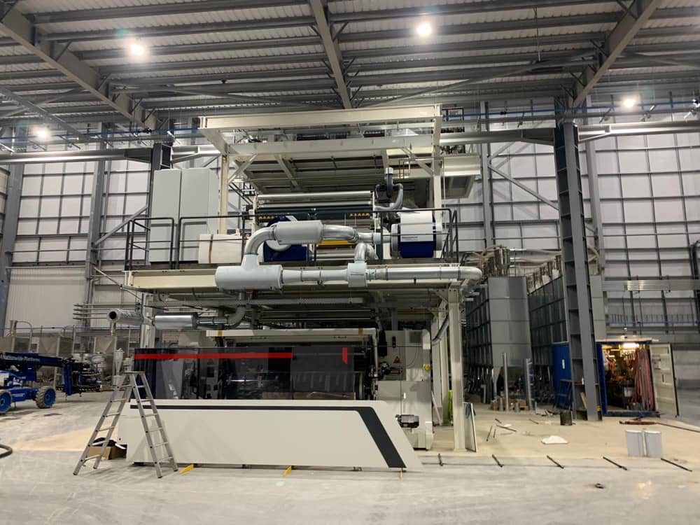 Montáž velké průmyslové tiskové nebo balicí linky v hale.